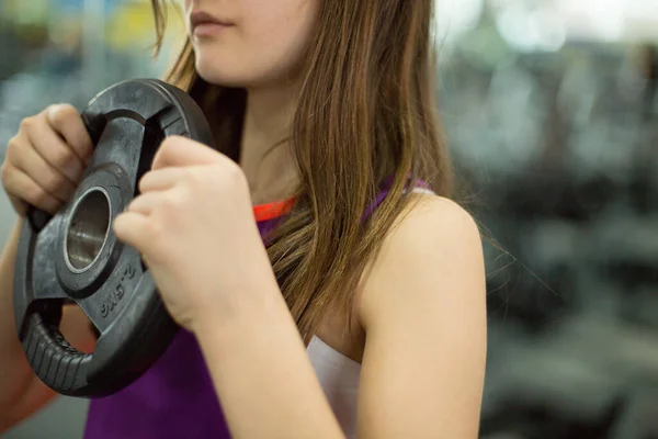 Teenage girl works out at the gym with weights