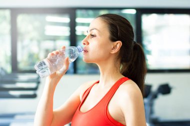 Kadın eğitimi. Spor salonundaki orta yaşlı kadın su içiyor.
