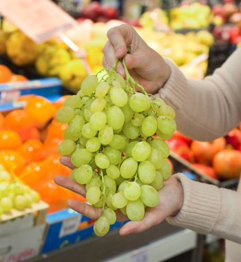 Kadın eli süpermarkette üzüm topluyor. Sağlıklı gıda kavramı, biyoloji, vejetaryen, diyet.
