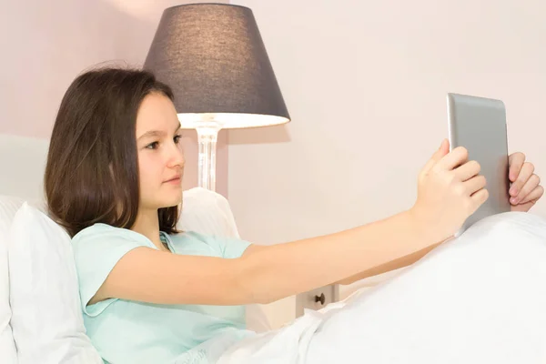 Bella Ragazza Adolescente Cerca Utilizzando Tablet Mentre Sdraiato Nel Letto — Foto Stock