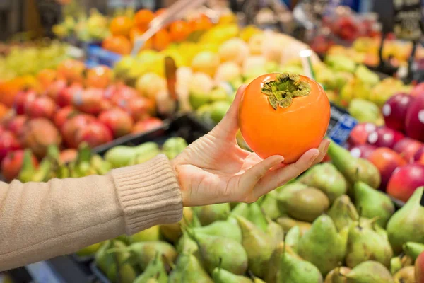 Süpermarkette kadın eli hurması. Sağlıklı gıda kavramı, biyoloji, vejetaryen, diyet.