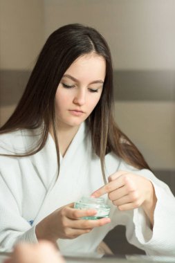 Kadın güzeli, güzel beyaz kadın evdeki banyoda yüzüne krem sürüyor.