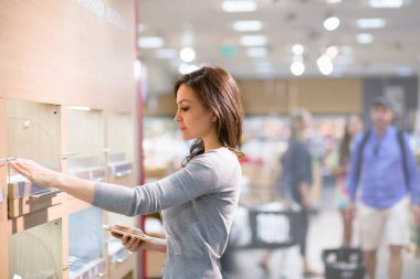 Kadın süpermarkette günlük ürünleri seçiyor. Ürün bilgileri okunuyor. Bilinçli sağlıklı yiyecek seçimi kavramı. 