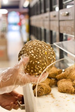 Piyasada ekmek seçen bir kadın. Kadın süpermarkette süt ürünleri seçiyor. Ürün bilgileri okunuyor