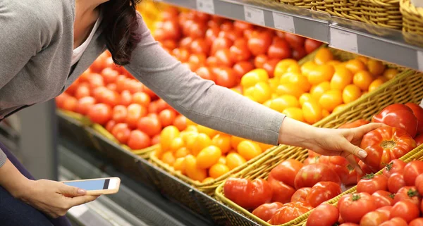 Woman choosing daily products in supermarket. Reading product information.Concept of conscious choice of healthy food