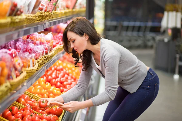 Woman choosing daily products in supermarket. Reading product information.Concept of conscious choice of healthy food