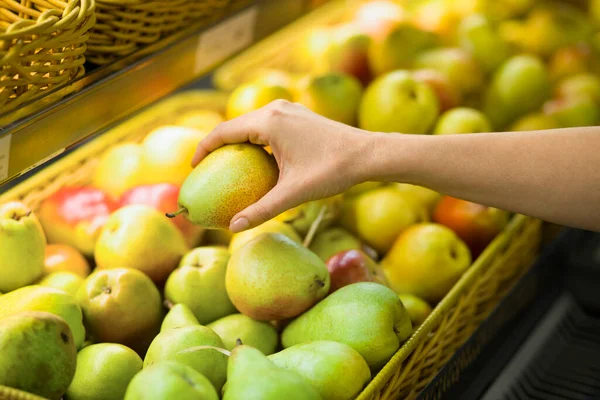 Kadın eli süpermarkette armut seçiyor. Sağlıklı gıda kavramı, biyoloji, vejetaryen, diyet.
