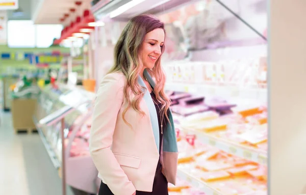 Woman choosing daily products in supermarket. Reading product information. Concept of conscious choice of bio and healthy food.