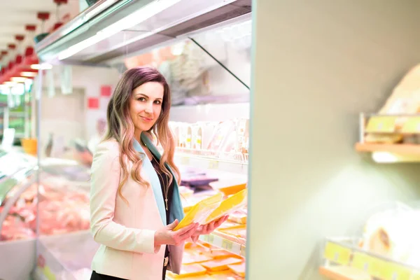 Woman choosing daily products in supermarket. Reading product information. Concept of conscious choice of bio and healthy food.