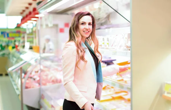 Woman choosing daily products in supermarket. Reading product information. Concept of conscious choice of bio and healthy food.