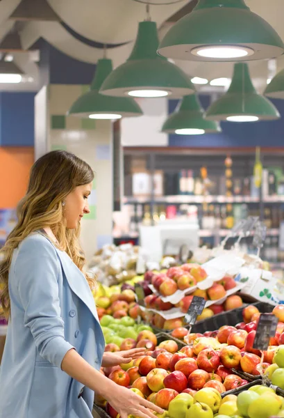 Woman choosing daily products at supermarket. Reading product information. Concept of conscious choice of bio, vegetarian, diet and healthy food.