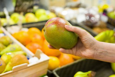 Markette mango seçen bir kadın eli. Sağlıklı gıda kavramı, biyoloji, vejetaryen, diyet.