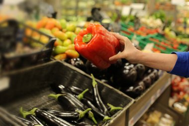 Kadının eli süpermarkette taze biber seçiyor. Sağlıklı gıda kavramı, biyoloji, vejetaryen, diyet.