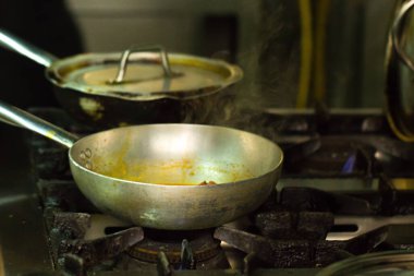 Mutfaktaki ocakta çelik tencereyle yemek pişirmek.