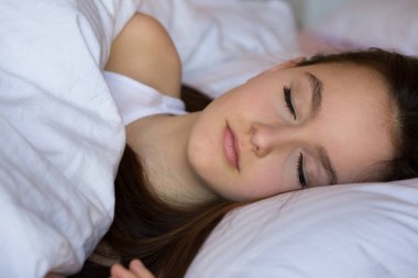 Uyuyan genç kız, sabahları rahat bir yatakta sağlıklı bir şekerlemenin tadını çıkarıyor. Milenyum kızı, yumuşak yastıkta dinleniyor ve beyaz pamuklu rahat bir yatak giyiyor..