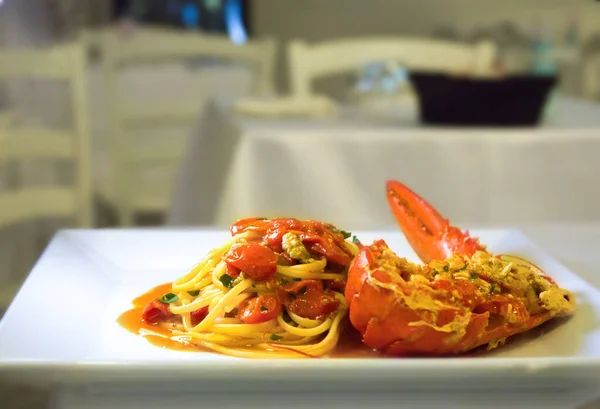 Beyaz tabakta servis edilen ıstakoz ve kiraz domatesli spagetti.