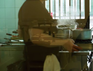 Aşçı bir restoranda yemek yapıyor. İş yerinde yemek hazırlayan bir kadın konsepti. Lokanta mutfağında yemek, meslek ve insan konsepti