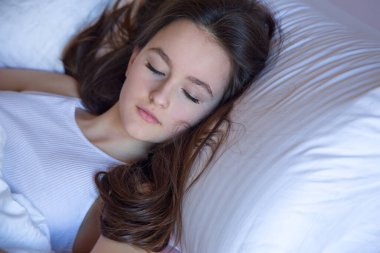 Uyandığında cep telefonu kullanan genç kız, sabah uyandığında cep telefonu kullanan kızın üzerinde mutlu hissediyor.