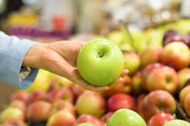 Kadının eli süpermarkette elma seçiyor. Biyolojik, vejetaryen, diyet ve sağlıklı besin seçimi kavramı