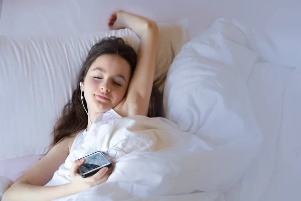 Teen girl using cell phone on waking feels happy in the morning on the beden girl using cell phone on waking feels happy in the morning on the bed