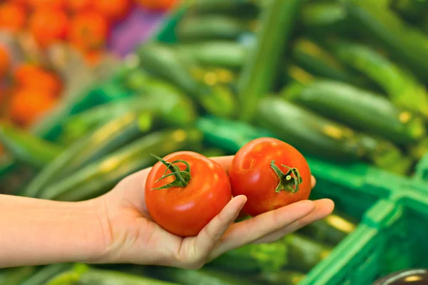 Woman\'s hand choosing tomato at supermarket