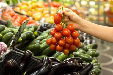 Kadın eli süpermarkette domates seçiyor. Sağlıklı gıda kavramı, biyoloji, vejetaryen, diyet.