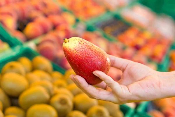 Süpermarkette mango seçen kadın eli. Sağlıklı gıda kavramı, biyoloji, vejetaryen, diyet.