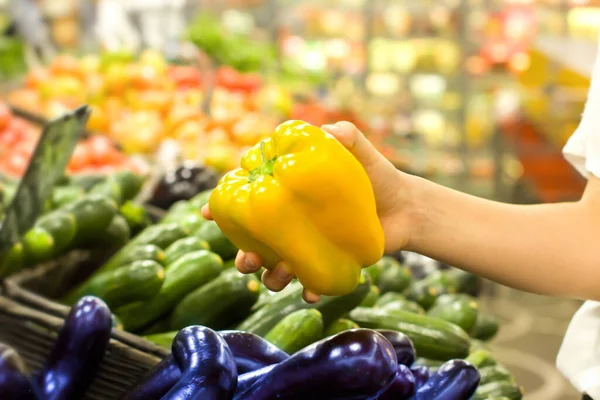 Female hand choosing pepper in supermarket. Concept of healthy food, bio, vegetarian, diet.
