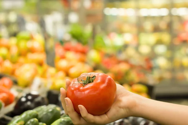 Kadın eli süpermarkette domates seçiyor. Sağlıklı gıda kavramı, biyoloji, vejetaryen, diyet.