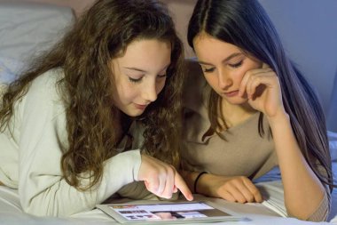 İki genç elinde bir tabletle internette sörf yapıyor. Video izlerler, birlikte vakit geçirirler ve eğlenirler..