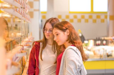 Teen girls shopping at the supermarket. Young people make the conscious, organic and healthy choice. clipart