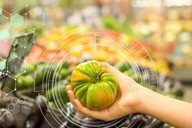 Kadın eli süpermarkette yeşil domates seçiyor. Sağlıklı gıda kavramı, biyoloji, vejetaryen, diyet.
