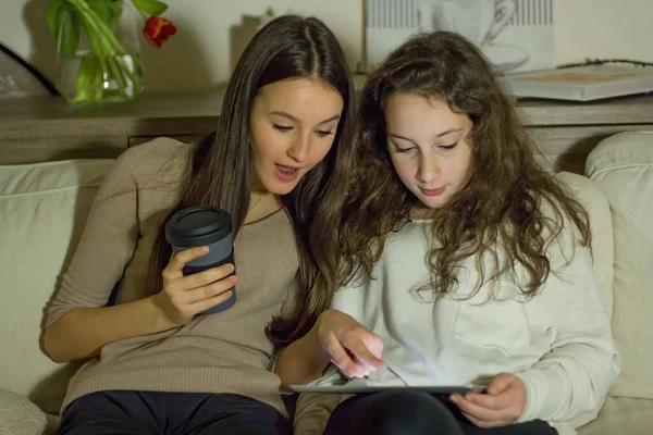 İki genç elinde bir tabletle internette sörf yapıyor. Video izlerler, birlikte vakit geçirirler ve eğlenirler..