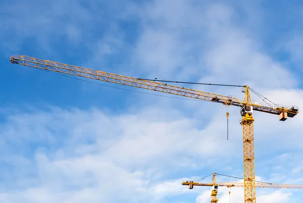 Bulutlar arka plan ile mavi gökyüzünde iki Liebherr vinç.
