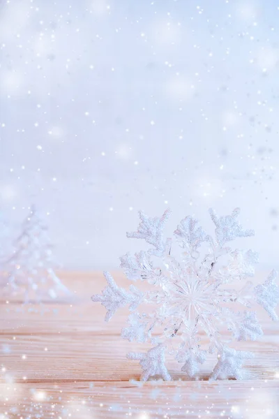 Floco de neve de brinquedo de Natal está em pé na mesa de madeira no fundo azul pálido com neve . — Fotografia de Stock