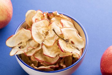 Mavi backgroun üzerinde elma cipsi ve taze elma ile Close-up fincan