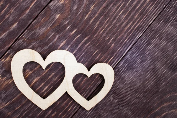 Dvě vyřezávaná dřevěná srdce leží na tmavých diagonálních prkněcích s prostorem pro kopírování. — Stock fotografie
