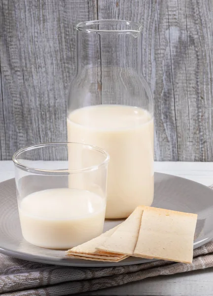 Close-up leite de aveia em garrafa de vidro e vidro em placa cinza sobre fundo de madeira cinza . — Fotografia de Stock