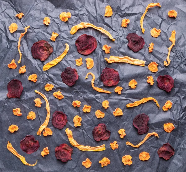 Образец овощных чипсов на смятой черной оберточной бумаге . — стоковое фото