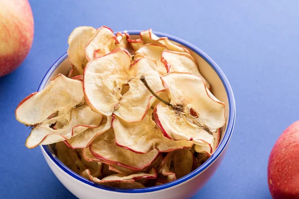 Mavi backgroun üzerinde elma cipsi ve taze elma ile Close-up fincan