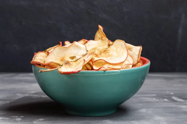 다크 그레이 배경에 사과 칩이 있는 청록색 세라믹 그릇 1개 닫기. — 스톡 사진