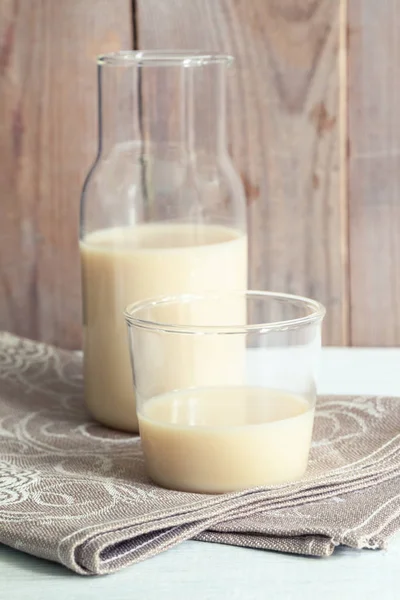 Close-up leite de aveia livre de leite em garrafa de vidro e vidro em guardanapo de linho no fundo de madeira . — Fotografia de Stock