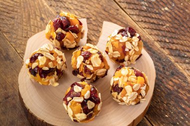 Altı ev yapımı enerji topları kahverengi ahşap masa üzerinde kesilmiş ahşap testere üzerinde yatıyor.