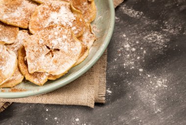 Burlap üzerine pudra şekeri ve tarçın serpilir elma cipsi ile yuvarlak yeşil plaka parçası.