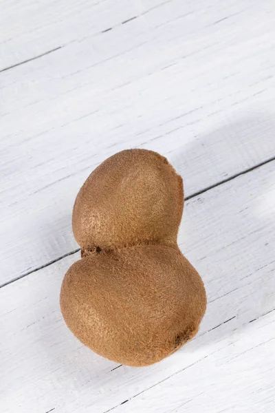 Egyetlen deformálódott conillesztett csúnya Kiwi a fehér fából készült asztal. — Stock Fotó