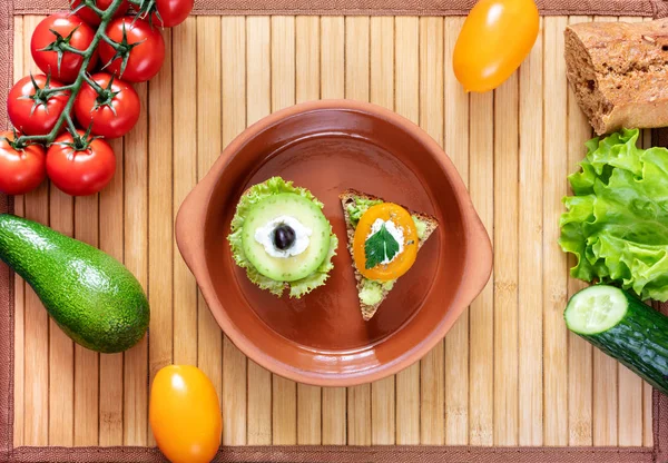 Dos sándwiches vegetarianos en plato de arcilla e ingredientes para cocinar en servilleta de bambú . —  Fotos de Stock