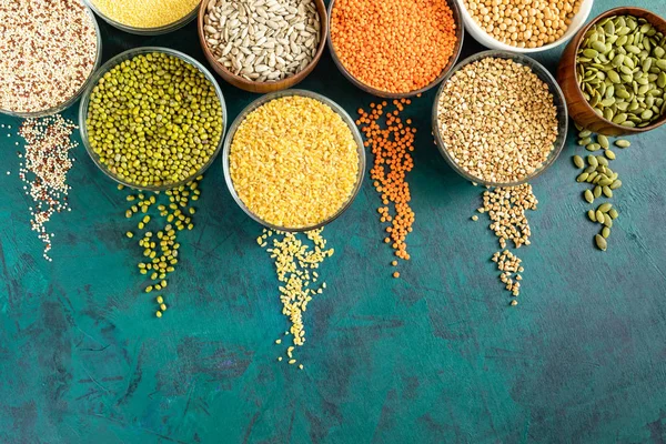 Zümrüt arka plan üzerinde superfoods ve dağınık tahıllar ile yuvarlak kase için üst görünümü.