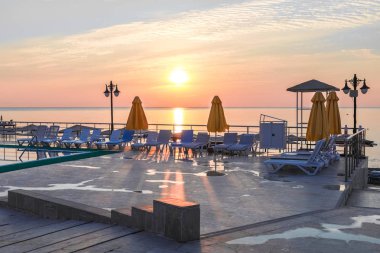 Güneş ışınları deniz manzarası şafak arka plan üzerinde beton güneşlenme alanı düşüyor.