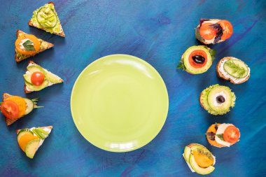 Üst görünüm vejetaryen sandviç ve mavi arka plan üzerinde yuvarlak yeşil plaka.