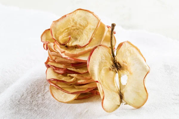 Vertical stack of apple chips and one slice standing near it on